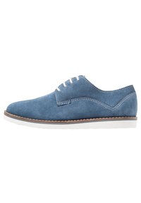 Scarpa oxford blu in suede con lacci bianchi, suola bianca e cuciture marroni a contrasto lungo il bordo. Design a profilo basso.