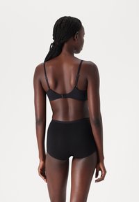Black bra with adjustable straps and hook closure, paired with high-waisted black underwear made of smooth fabric, offering full coverage.