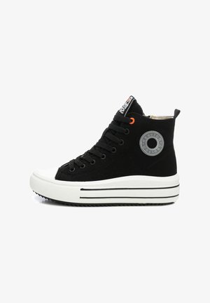 Zapatilla alta negra con suela de goma blanca plana, ojales negros, acento naranja y detalle del logo circular en el lateral.