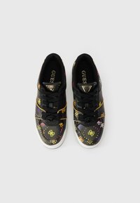 Ténis pretos com acabamento brilhante, apresentando padrões e logótipos coloridos, atacadores redondos e uma sola texturada. Acentos dourados na língua.