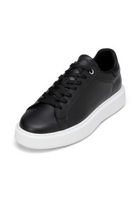 Baskets en cuir noir avec lacets noirs et semelle épaisse en caoutchouc blanc, légèrement inclinées pour montrer les détails avant et latéraux.