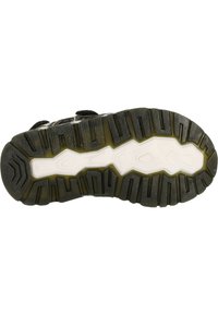 Svart gummisul med uttalade mönster, försedd med en vit mellansula och texturerade spår för grepp. Designad för hållbarhet och fäste.