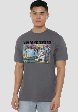Man wearing gray T-shirt with "Where the Wild Things Are" text and illustration of a boat, trees, and a large creature.