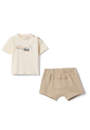 Maglietta cremosa per bambini a maniche corte con due bottoni in legno e illustrazioni di automobili, abbinata a pantaloncini beige con vita elasticizzata e tasca posteriore.