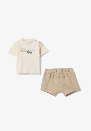Maglietta cremosa per bambini a maniche corte con due bottoni in legno e illustrazioni di automobili, abbinata a pantaloncini beige con vita elasticizzata e tasca posteriore.
