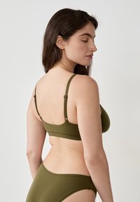 Das olivgrüne Unterwäsche-Set besteht aus einem nahtlosen BH mit verstellbaren Trägern und passenden hochgeschnittenen Slips, gefertigt aus einem glatten, elastischen Stoff.