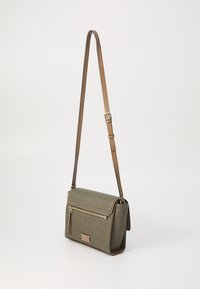 Textured olive green crossbody bag with brown leather accents, adjustable strap, front zip pocket, and a flap closure.