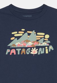 T-maica kratkih rukava tamnoplave boje s grafikom šarenih planina i krajolika. Natpis glasi "PATAG" s naglaskom na list. Od pamučnog materijala.