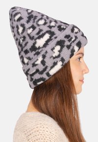 Graue Strickmütze mit schwarz-weißer Leopardenmuster, mit weicher Textur und lässigem Design, schräg getragen.