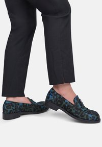 Luipaardprint loafers met een zachte textuur in groene en blauwe tinten. Het ontwerp heeft een klassieke vorm en een lage zwarte hak.