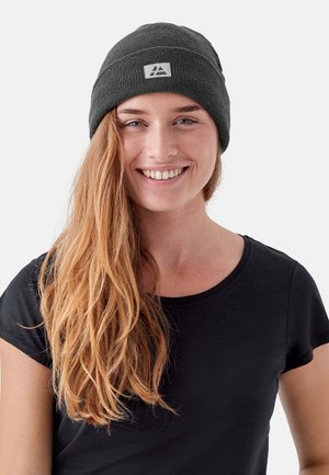 Grijze gebreide beanie met een omgeslagen rand en een klein driehoekig logo patch. Gladde textuur, gedragen met een zwart T-shirt met korte mouwen.
