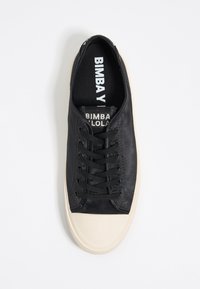 Sneaker nera con tomaia in tessuto morbido, lacci neri e suola in gomma bianca a contrasto. Marchio visibile sulla soletta.