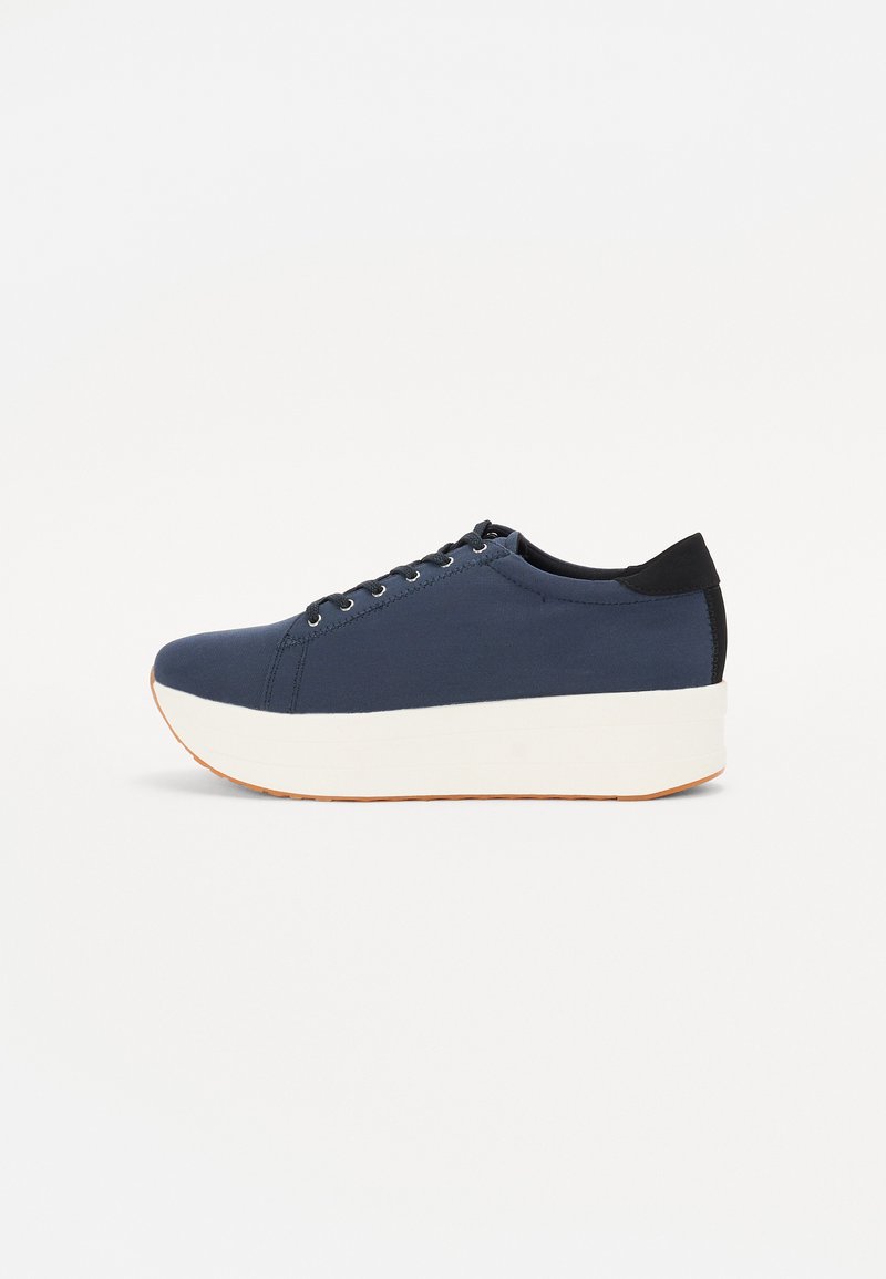 Zapatilla de color azul marino con parte superior de tejido texturizado, suela de plataforma blanca, punta redondeada y acento en el talón negro. Cuenta con seis ojales para los cordones.