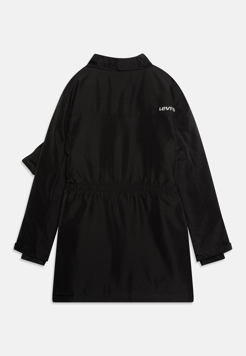 Manteau en tissu noir avec un col, taille élastique et logo Levi's en blanc dans le haut du dos. Manches longues avec détails aux poignets.