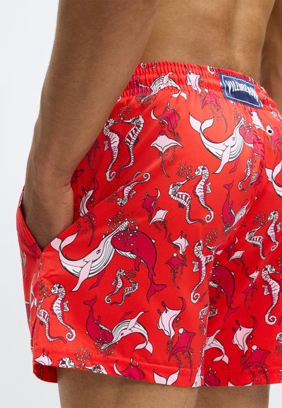 Raudoni maudymosi šortai su žaismingu jūrų gyvybės raštu, kuriame yra banginių, jūros arkliukų ir manta spindulių. Pagaminti iš lengvos, greitai džiūstančios medžiagos.