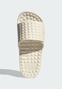 Adidas-sandaalit vaaleassa valkoisessa, joissa on pehmustettu hihna tekstuuripinnalla, muotoiltu pohja ja pistekuviointi pitoa varten.