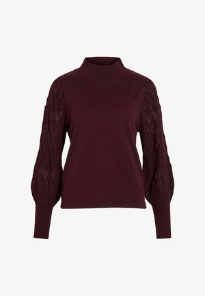 Burgundska pulover s visokim ovratnikom, strukturiranim trakom in zapleteno pletenimi pufastimi rokavi, ki prikazujejo diamante. Mehka tekstura.