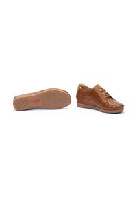 Zapatos de cuero marrón con diseño perforado, cierre con cordones, forma afilada y suela de goma texturizada. Presenta un ligero tacón para dar elevación.