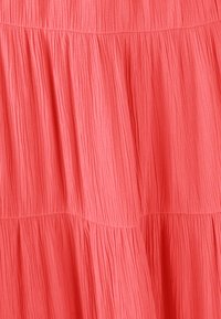 Robe corail à étages avec un tissu texturé et plissé, de douces couches fluides et une taille élastique pour plus de confort et de flexibilité.