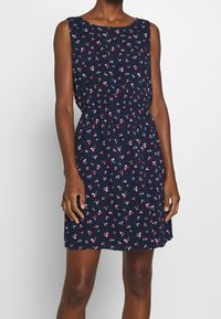 Sukienka bez rękawów w granatowym materiale w kwiatowy nadruk, z małymi wielokolorowymi kwiatami, elastyczną talią i luźnym krojem.