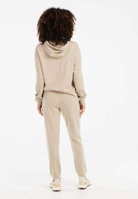 Beige Kapuzenpullover und passende Jogginghose aus weichem Material. Verfügt über eine lockere Passform, gerippte Bündchen und einen elastischen Taillenbund.