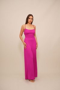 Fuksia jumpsuit dengan tali spaghetti tipis, bodice yang pas, dan celana lebar yang terbuat dari kain halus.