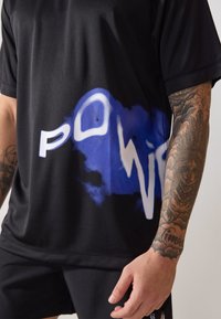 Schwarzes Sport-T-Shirt mit einem blau-weißen Grafikdesign und dem Wort "POWER". Kurzärmlig und aus strukturiertem Stoff.