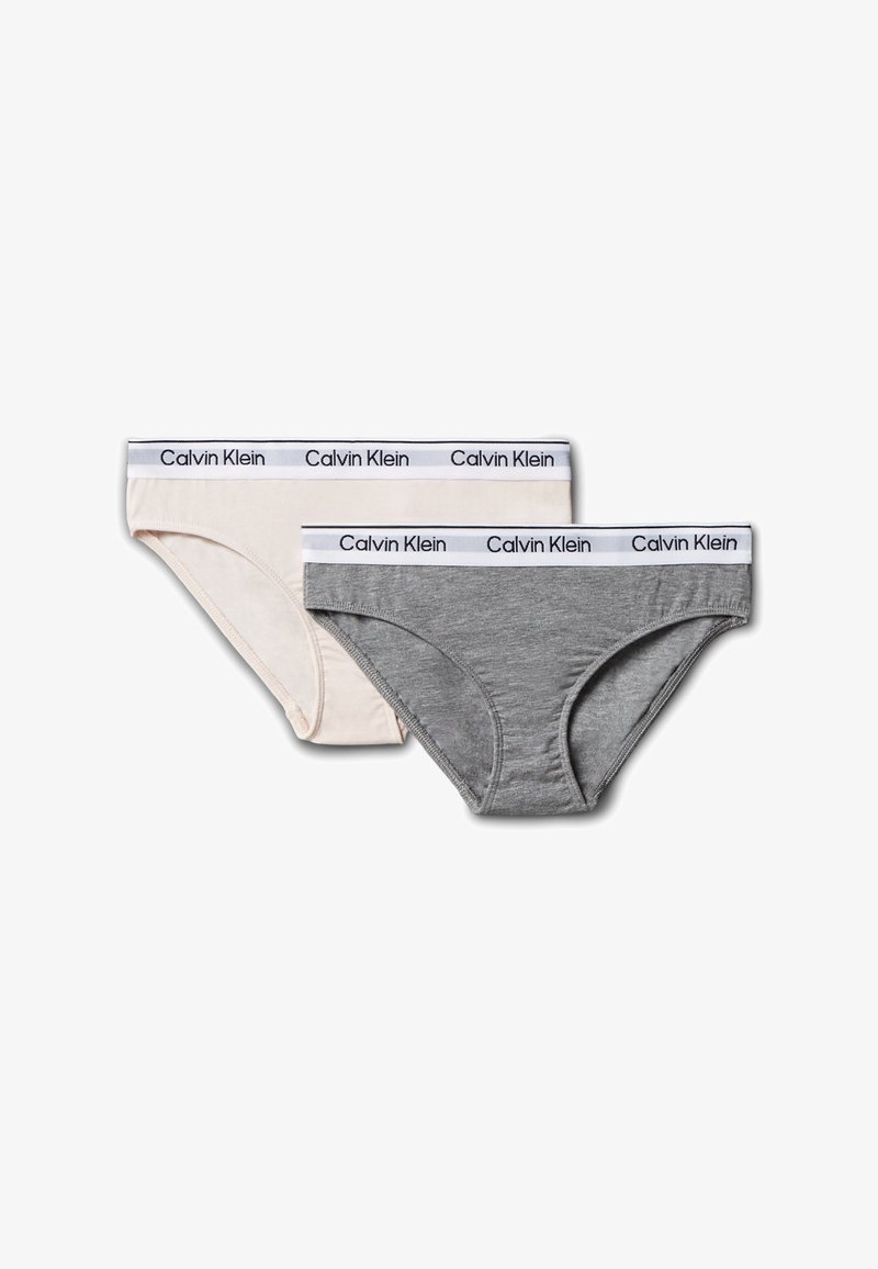 Dwa bikini Calvin Klein, jeden beżowy, drugi szary, oba z białymi elastycznymi pasami w talii z nazwą marki w czerni.