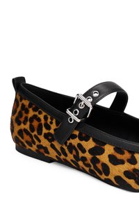 Chaussure plate en tissu imprimé léopard, bride en cuir noir avec boucle argentée et bordure noire le long de l'ouverture.