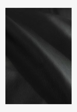 Černá kůže s texturou a měkkým matným povrchem, ukazující různé odstíny černé podél záhybů a vrásčin.