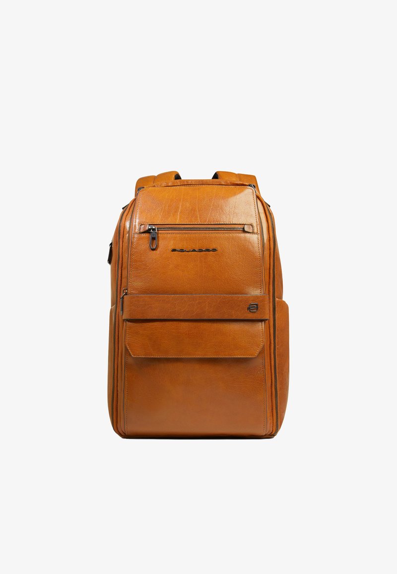 Sac à dos en cuir marron avec une poche avant zippée, une poche à rabat et des bretelles rembourrées, debout sur un fond blanc.