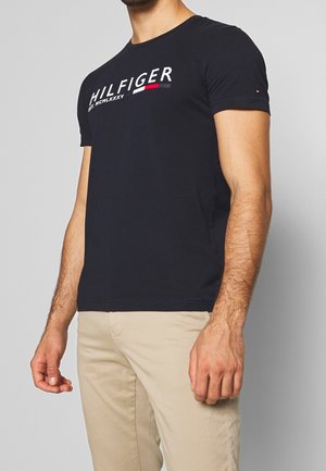 Maglietta in cotone blu navy con maniche corte, con la scritta "HILFIGER EST. MCNLXXXV" in bianco e rosso, scollatura rotonda, design aderente.