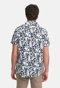 Camicia a maniche corte in navy con motivo floreale bianco, realizzata in tessuto leggero. Presenta un colletto a camicia e una vestibilità relax.