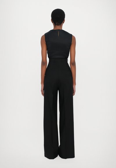 Black sleeveless top with back slit detail paired with high-waisted, wide-leg black pants, featuring pockets and smooth fabric texture.