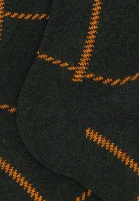 Calze nere con linee arancioni cucite che formano motivi astratti su tessuto a maglia.