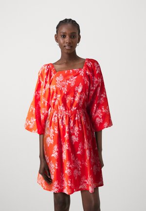 Red floral dress with puff sleeves, square neckline, gathered waist, and knee-length hem. Fabric features a white floral pattern throughout.