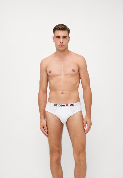 Fehér pamut alsónadrág fekete derékkal, amelyen a "MOSCHINO ❤️ YOU" felirat szerepel. Simaság jellemzi, testhez álló kialakítással és középhasú fazonnal.