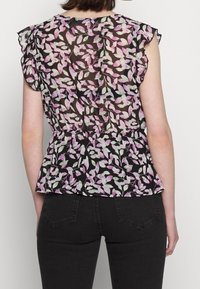 Blouse noire en tissu transparent avec un motif floral aux teintes roses et vertes, dotée de manches courtes à volants et d'une taille cache-cœur évasée.
