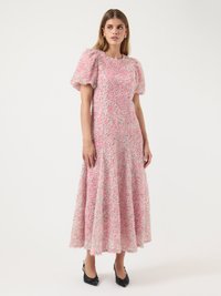 Rosa teksturert midikjole med puff-sleeves og en utsvingt skjert, med et flerfarget mønster. Brukt med svarte spisse hæler.