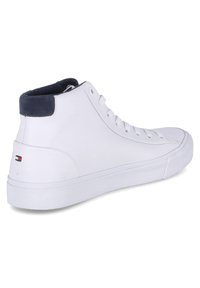 Zapatilla alta blanca hecha de cuero liso, con un acento de ante azul marino en el cuello y un pequeño detalle de logo en el talón.