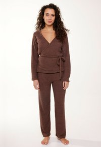 Brown, fluffy loungewear set featuring a wrap-top with long sleeves and a tied waist, paired with loose-fitting, textured pants.