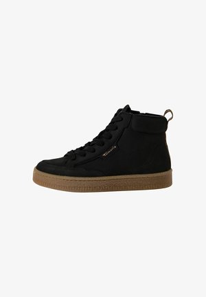 Baskets montantes noires en daim avec une semelle en caoutchouc texturée beige, dotées de lacets noirs, d'un logo sur le côté et d'une languette au talon.
