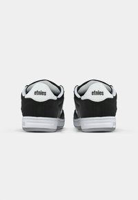 Crne kožne tenisice s bijelim detaljima; imaju podstavljeni ovratnik i jezik, teksturiranu potplat i 'etnies' logo na peti i jeziku.