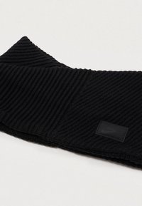 Fular negru din tricot cu nervuri, cu un finisaj texturat și un mic patch cu logo negru. Material moale, formă rotundă, potrivit pentru vreme rece.