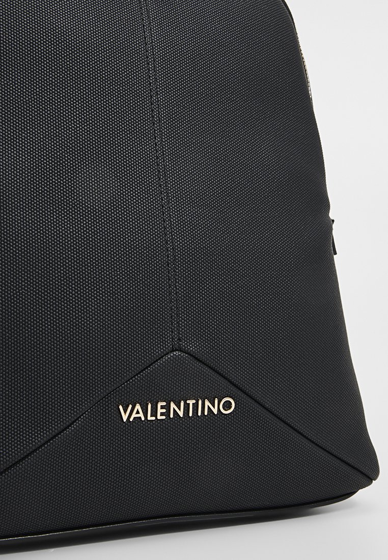 Schwarze, strukturierte Stofftasche mit einem goldenen "VALENTINO"-Logo am Boden. Das Design ist kantig mit mattem Finish und subtiler Ausstrahlung.