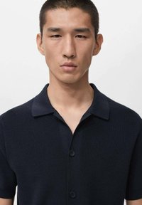 Polo a maniche corte blu navy con trama a coste, abbottonatura e colletto piatto, progettata per una silhouette aderente.