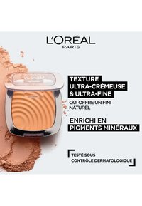 Poudrier L'Oréal Paris avec un couvercle translucide, contenant de la poudre beige clair avec des motifs ondulés subtils, entourée de poudre libre.