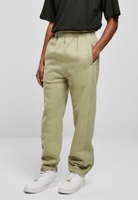 Light green sweatpants with an elastic waistband, side pockets, and tapered cuffs. Smooth texture, sturdy fabric with no visible patterns.