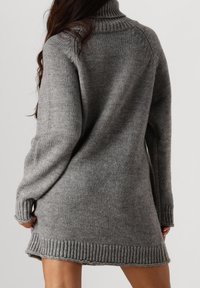 Grijze gebreide sweaterdress met een hoge col, geribbelde manchetten en zoom. Heeft een relaxed fit en een gestructureerd materiaal.