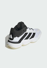 Chaussure de sport blanche avec accents noirs et trois bandes. Présente un dessus texturé, un col rembourré et une semelle épaisse blanche.